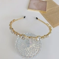 Elegant gold headband with geometric rhinestones displayed on a glass base - White