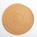 Handwoven round cotton cord table mat in natural brown featuring spiral braided texture - Earthy Yellow