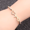 Bracciale in rame con ciondoli a cuore e zampa in zircone indossato su sfondo scuro - Catena di Perline Tricolore + Impronta del Cuore