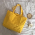 Vue détaillée du sac fourre-tout minimaliste en toile jaune vif dans un décor chic - Jaune