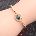 Détail d'un bracelet cordon rouge avec perles dorées et zircon œil bleu sur poignet - Cordon Rouge Perles Mauvais Œil Style 1