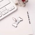 Detailed view of a silver bone-shaped pet tag with white paw print and metal ring attachment - 30*15mm / White
