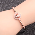 Roségouden kralenarmband met micro-pave schedelhanger op donkere glitterachtergrond - Roségoud