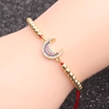 Micro-pave zircon moon charm bracelet with gold beads and red woven cord on wrist - Red Rope Copper Bead Moon