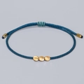 Handmade woven navy blue Tibetan bracelet with three gold beads on a grey background - Dark Blue