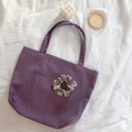 Minimalist purple canvas tote bag with floral scrunchie on soft white fabric background - Purple