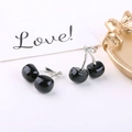 Detailed macro view of black acrylic cherry charms with silver stems and bow detail - Black