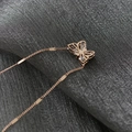 Gros plan du pendentif papillon en or rose serti de zircons sur tissu en soie - Or rose