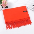 Elegant orange cashmere scarf with fringe details and woven brand label on white surface - Orange