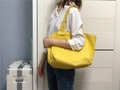 Grote gele canvas shopper gedragen door model voor dagelijkse casual en shoppingstijl - Mangogeel
