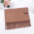 Folded camel cashmere scarf with tassels and black material label on white surface - Camel