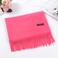 Pink cashmere scarf with tassels and brand label, styled with pink roses on the side - Watermelon red