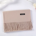 Elegant beige cashmere scarf with tassels and stitched label, folded on a decorative surface - Light Camel