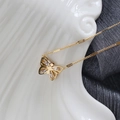Detail van een 18K vergulde vlinderketting met fonkelende zirkoon op wit porselein - Goud