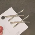 Paar goudkleurige X-vormige haarspelden met fonkelende witte kristallen op kaartje - Kruis Haarclips - Set van 2
