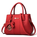 Elegant red faux leather handbag with diamond-quilted pattern and heart charm pendant - Red