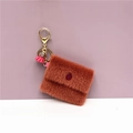 Dettaglio del mini portamonete in peluche con nappa rosa e clip per chiavi dorata - Rosso Mattone
