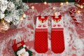 Detail of red Christmas socks with knitted cartoon reindeer patterns and festive textures - One Size / Red and White Fox
