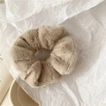 Detail view of a plush beige scrunchie made of soft faux fur for autumn winter hair styling - Brown