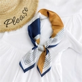Elegant navy blue and yellow geometric silk scarf for women displayed with a straw hat - Geometric Orange Navy