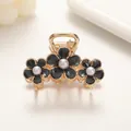 Detail view of triple floral hair claw clip with black petals and central pearls - Medium / Black