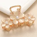 Macro shot of gold alloy hair claw with three cream enamel flowers and white pearls - Large / Off-white