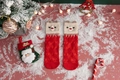 Close-up of red and beige knitted Christmas socks with cartoon reindeer on fake snow - One Size / Red Beige Reindeer