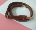 Close-up of brown PU leather bag strap with adjustable golden metal buckles and lobster clips - Brown