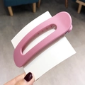 Pink matte plastic large hair claw clip held by hand against a soft background - Pink