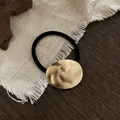 Minimalistische zwarte haarelastiek met een matgouden getextureerde metalen decoratie - Goud Gehamerde Ovaal