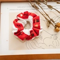 Detail eines roten Weihnachts-Scrunchie mit goldenem Druck und weißem Plüsch-Innenband - Weißes Haargummi mit rotem Band