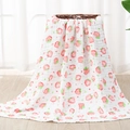 Soft six-layer cotton muslin baby blanket with red strawberry print over a woven basket - Strawberry