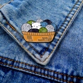 Detail of cute cat in yarn basket enamel pin pinned on a blue denim jacket pocket - White Cat in Yarn Basket