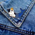 Detail of a cat mermaid enamel pin with gold metal edges pinned on a blue denim jacket - Mermaid Cat