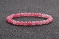 Détail du bracelet en perles d'agate rose de 6mm sur fond noir pailleté avec 24 perles lisses - Rose