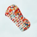 Detailed macro view of curved wide-tooth acetate comb with floral marble pattern - Orange Red
