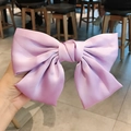Barrette à grand nœud en satin violet clair tenue en main montrant la texture de soie lisse - Clip à ressort en satin / Lilas (Satin)