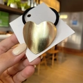Detail view of golden heart metal charm hair tie with brushed texture on white card - Heart