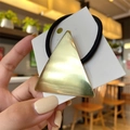 Minimalistisches goldenes Dreieck-Haargummi mit schwarzem Elastikband auf Karte - Dreieck