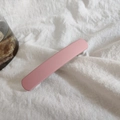 Dettaglio molletta per capelli in acrilico rosa opaco su tessuto bianco - Rosa