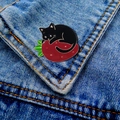 Detail of cartoon black cat on strawberry enamel pin brooch on blue denim jacket - Black Cat Strawberry-Gold Edge