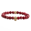Bracciale di pietre imperiali rosse da 8mm con ciondolo a teschio dorato su sfondo bianco - Teschio in Pietra dell'Imperatore Rosso