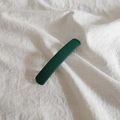 Vista macro di una lunga clip per capelli verde scuro opaco su lino bianco - Verde