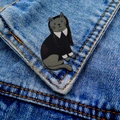 Detalle de un pin esmaltado de gato inspirado en Wednesday Addams sobre tela vaquera - Gato Estilo Wednesday