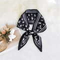 Elegant black silk scarf featuring white skull prints and stripe borders in a knotted style - Skull Black