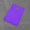 Flat lay of a purple PE plastic shopping bag with a die-cut handle on a textured background - Purple