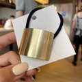 Detailed view of golden brushed metal arch buckle on elastic hair tie with white card - Square