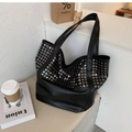 Macro detail of black tote bag featuring metallic silver studs and premium leather texture - Black