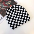 Detail of black and white checkerboard knit beanie with magazine as fashion prop - Checkered