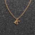 Close-up of golden stainless steel necklace with letter E pendant on black background - Gold E